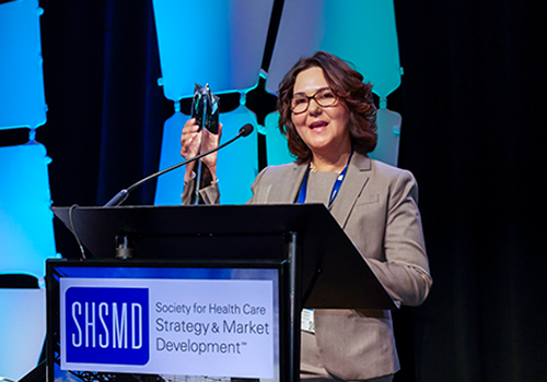 a woman standing at podium holding award