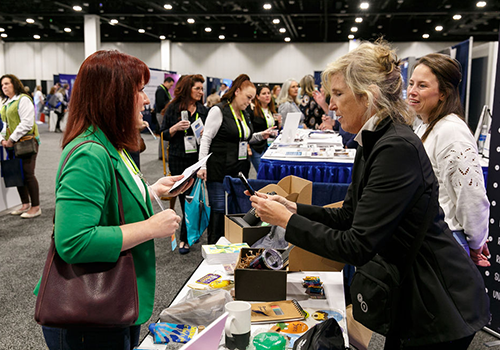 three people networking and exchanging information at an exhibitor table in a conference hall