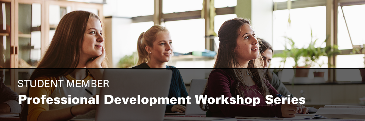 four students sitting in class taking notes on laptop and paper